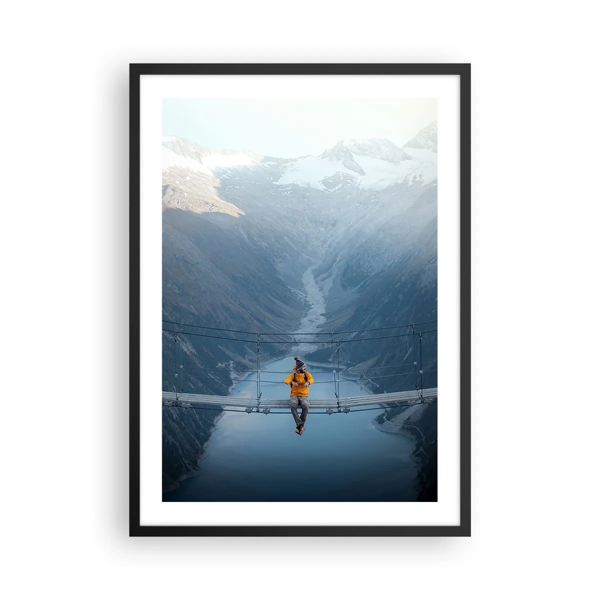 Poster in einem schwarzem Rahmen - Eine Person in einer gelben Jacke sitzt auf einer Hängebrücke über einem Tal - 50x70cm - Entzückt in der Schwebe - Moderne Wanddekoration für Wohnzimmer und Schlafzimmer ARTTOR