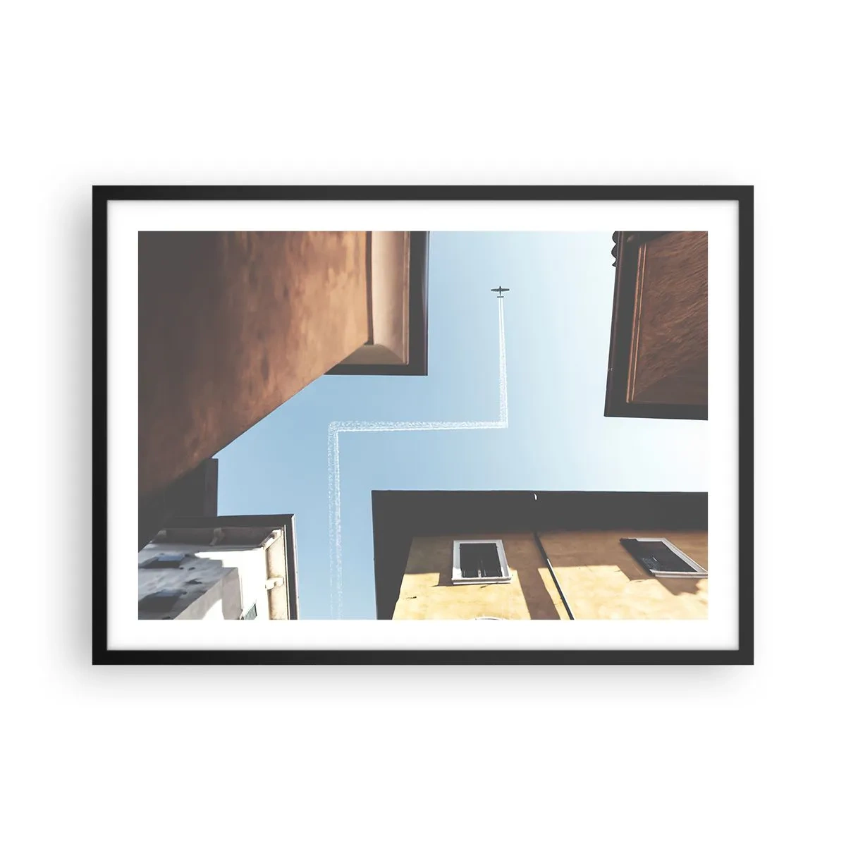 Poster in einem schwarzem Rahmen - Blick auf das Flugzeug und seine Spur am Himmel aus der Straßenperspektive - 70x50cm - Über dem Stadtlabyrinth - Moderne Wanddekoration für Wohnzimmer und Schlafzimmer ARTTOR