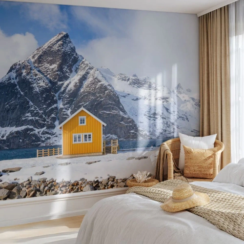 Fototapete Premium Canvas - Ein gelbes Haus vor der Kulisse schneebedeckter Berge und des Meeres - 100x70cm - Skandinavische Feiertage - Moderne Wanddekoration für Wohnzimmer und Schlafzimmer ARTTOR