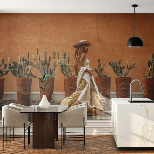 Fototapete Premium Sand - Eine Frau im Boho-Stil vor dem Hintergrund von Kakteentöpfen und einer orangefarbenen Wand. - 100x70cm - Hippie-Stil - Moderne Wanddekoration für Wohnzimmer und Schlafzimmer ARTTOR