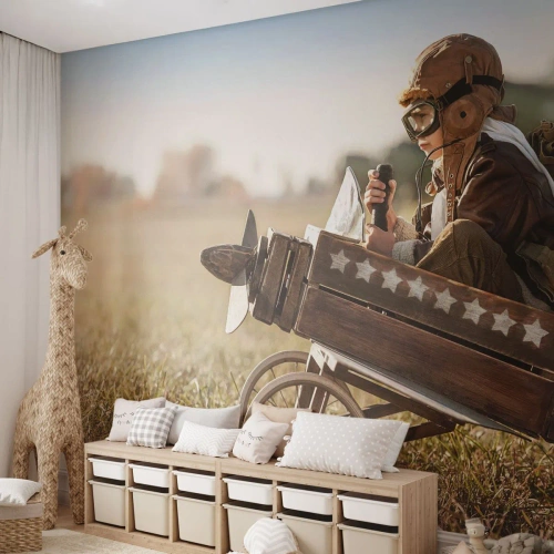 Fototapete Premium Sand - Kind im Pilotenkostüm in Holzflugzeug auf Feld - 100x70cm - Start in Richtung eines Traums - Moderne Wanddekoration für Wohnzimmer und Schlafzimmer ARTTOR