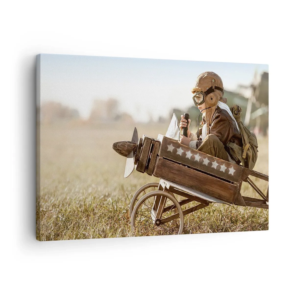 Bild auf Leinwand - Leinwandbild - Ein Kind in einem Spielzeugflugzeug mit einem Feld im Hintergrund - 70x50cm - Start in Richtung eines Traums - Moderne Wanddekoration für Wohnzimmer und Schlafzimmer ARTTOR