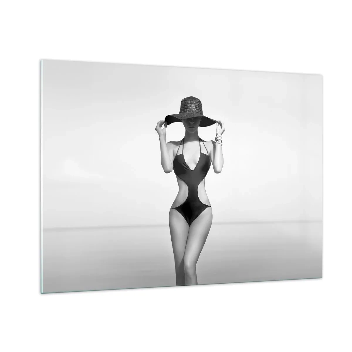 Glasbild - Bild auf glas - Eine Frau in einem schwarzen Badeanzug und Hut vor dem Meer - 100x70cm - Mein Name ist: Eleganz - Moderne Wanddekoration für Wohnzimmer und Schlafzimmer ARTTOR