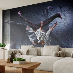 Fototapete Premium Canvas - Eine Tänzerin bei einem dynamischen Sprung gegen eine Ziegelmauer - 100x70cm - Straßenstar - Moderne Wanddekoration für Wohnzimmer und Schlafzimmer ARTTOR