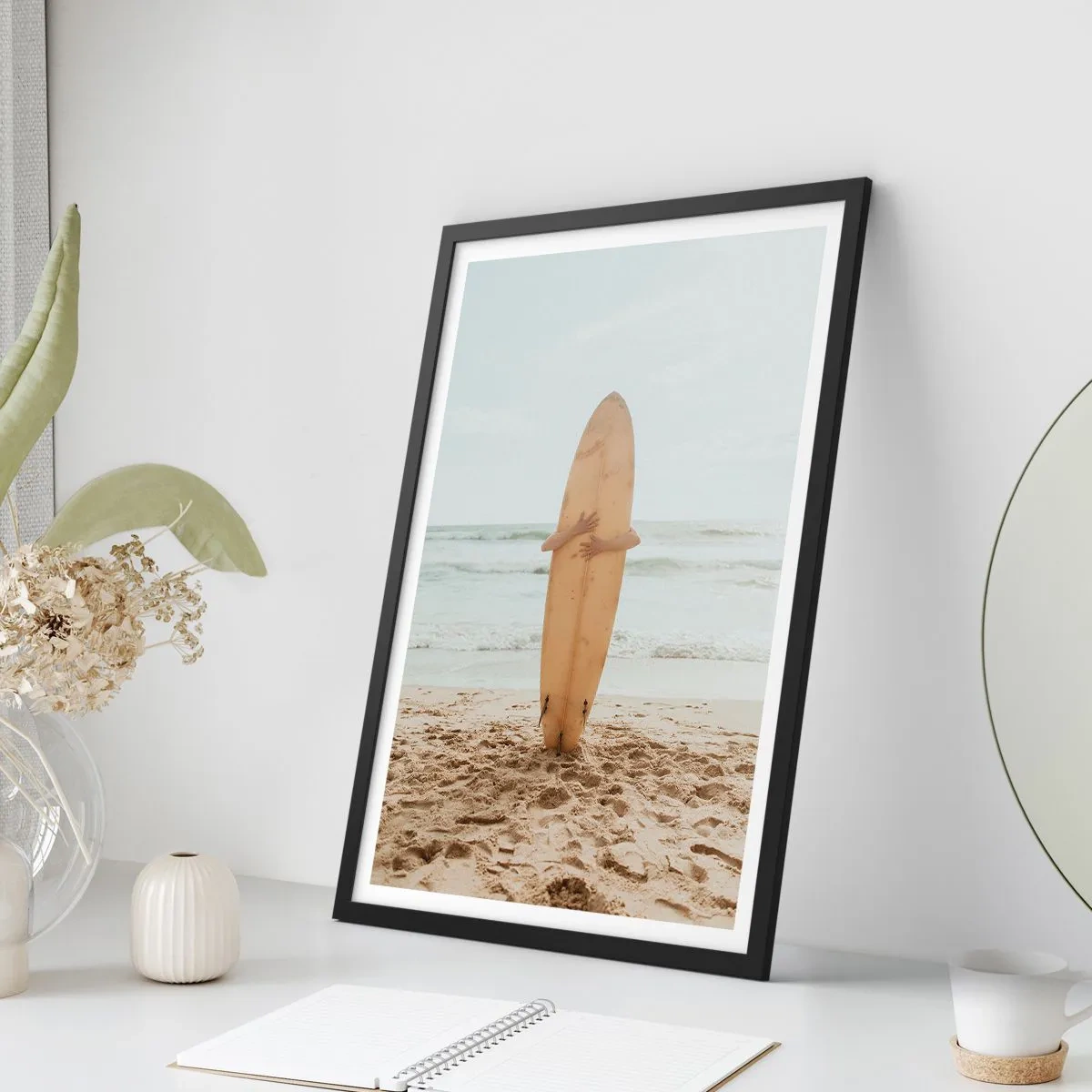 Poster in einem schwarzem Rahmen - Eine Person hält ein Surfbrett an einem Strand und blickt auf das Meer. - 50x70cm - Aus Liebe zu Wellen - Moderne Wanddekoration für Wohnzimmer und Schlafzimmer ARTTOR
