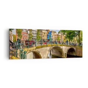 Bild auf Leinwand - Leinwandbild - Ein malerischer Kanal mit einer Brücke in Amsterdam - 140x50cm - Frühling am Kanal - Moderne Wanddekoration für Wohnzimmer und Schlafzimmer ARTTOR